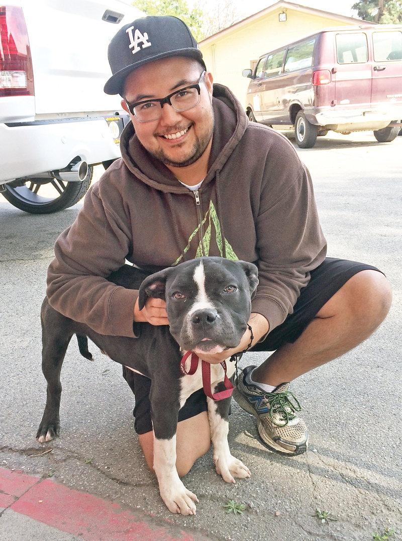 a man kneels next to a dog