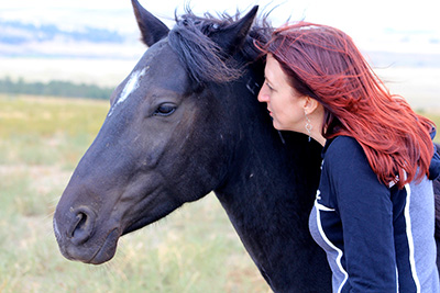 a woman standing alongside a horse