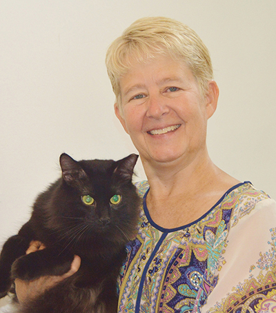 Portrait of Karen Little holding a black cat.