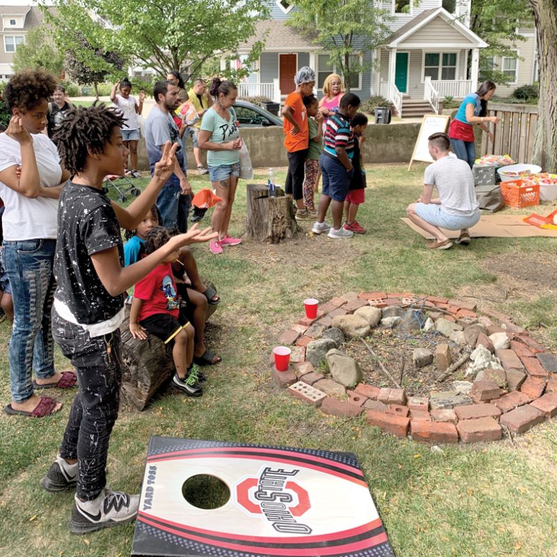 a group of people gathered around a fire pit and lawn games