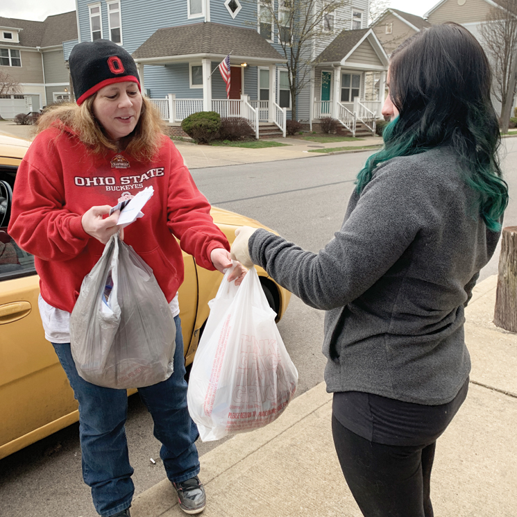 a woman hands another woman plastic bags