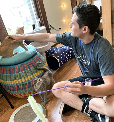 A man sitting on the floor petting a cat.