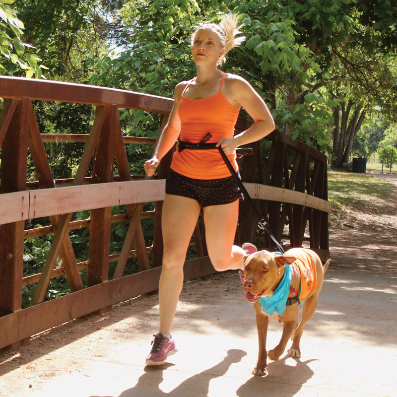 a woman running with a dog on a bridge