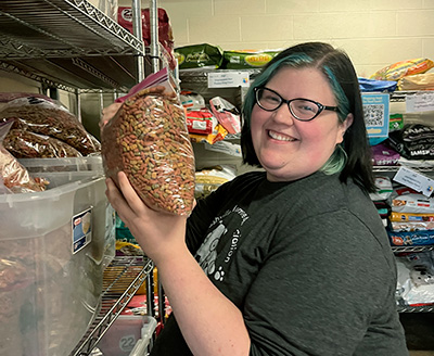 a woman holding a bag of pet food in a pantry