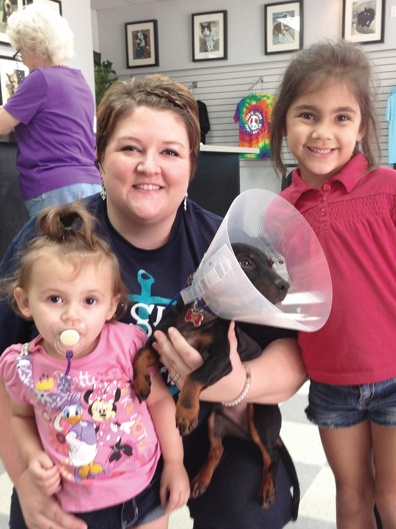 a woman and two young children pose with a puppy