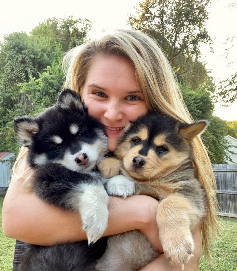 a woman hugs two puppies