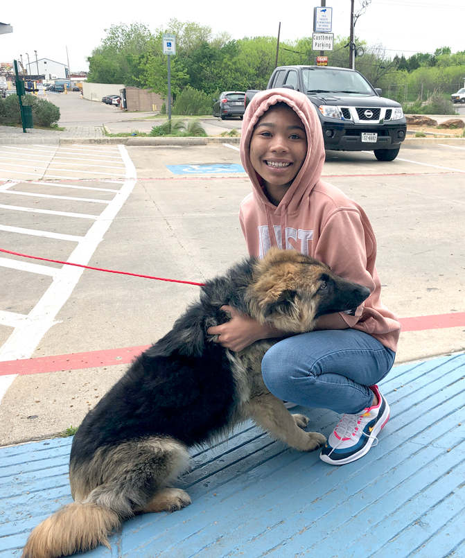 a teenage girl kneeling alongside her dog