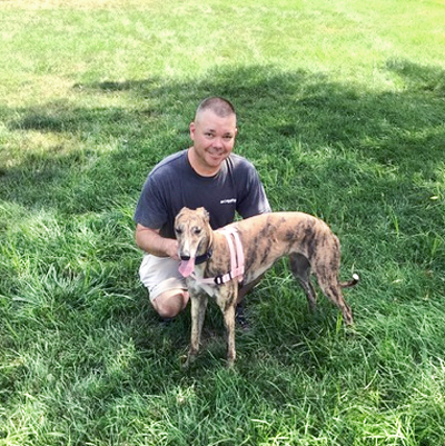a man posing with his greyhound