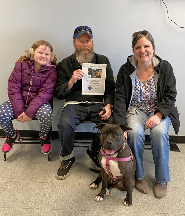 a family poses with their dog