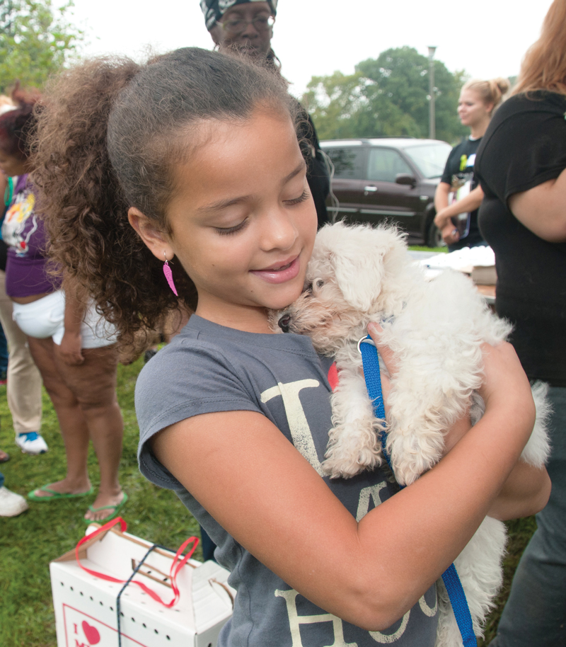 a young girl carries her dog