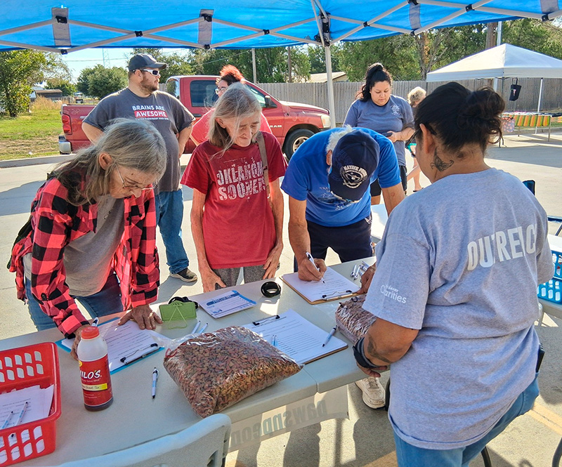 people stand in line in front of a table waiting to pick up pet food