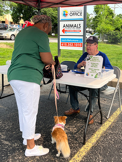 a woman and her dog stand in line behind a table