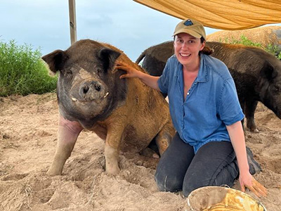 a woman kneeling alongside a pig
