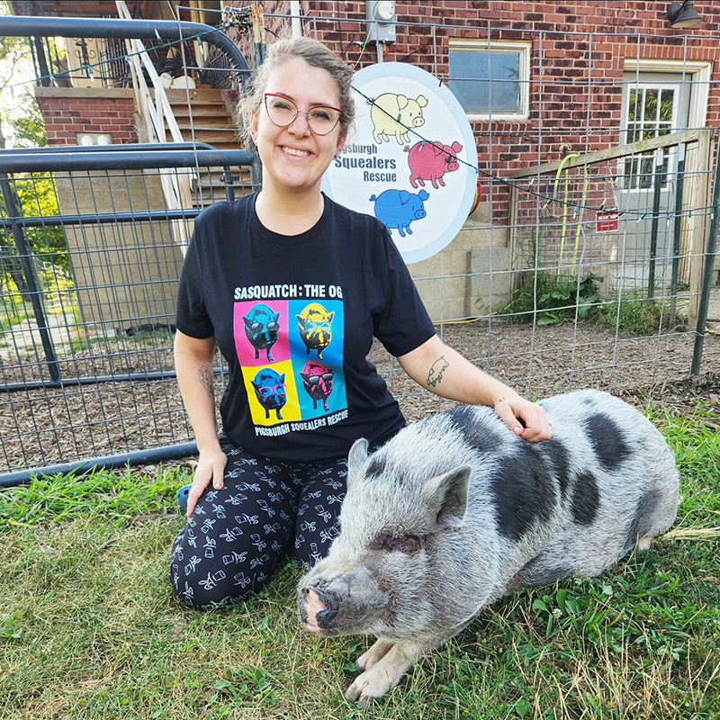 a woman kneeling alongside a pig