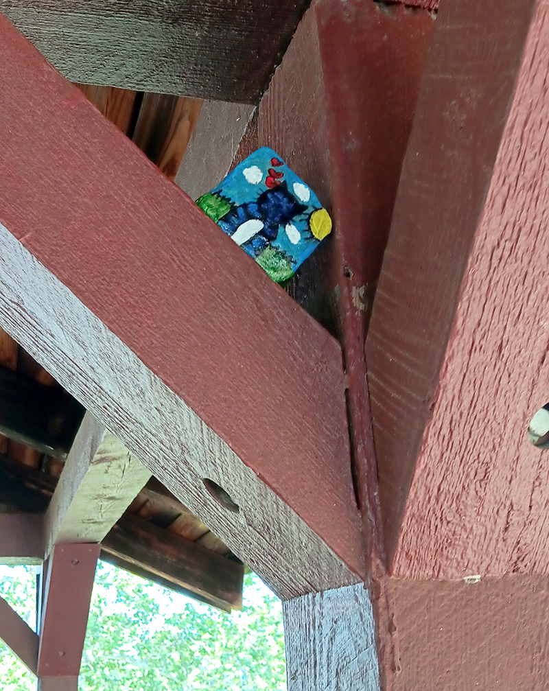 a painted rock hidden atop roof rafters in an outdoor building