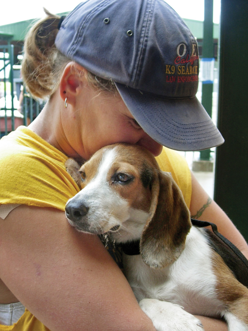 a woman hugs a beagle type dog