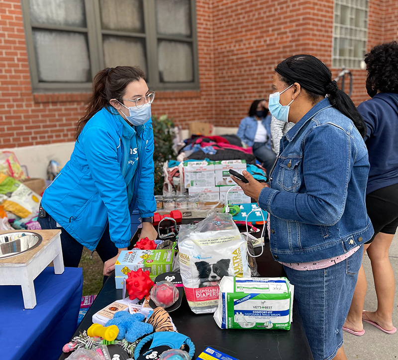 two women chatting over a large table filled with pet supplies
