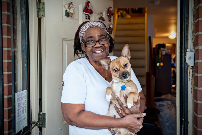 a woman stands in her doorway holding her dog