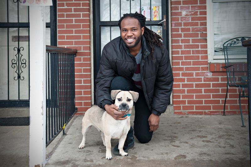 a man poses with his dog on a porch stoop