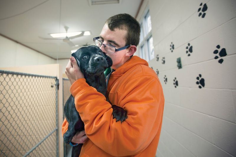 a man holds a dog and kisses its head