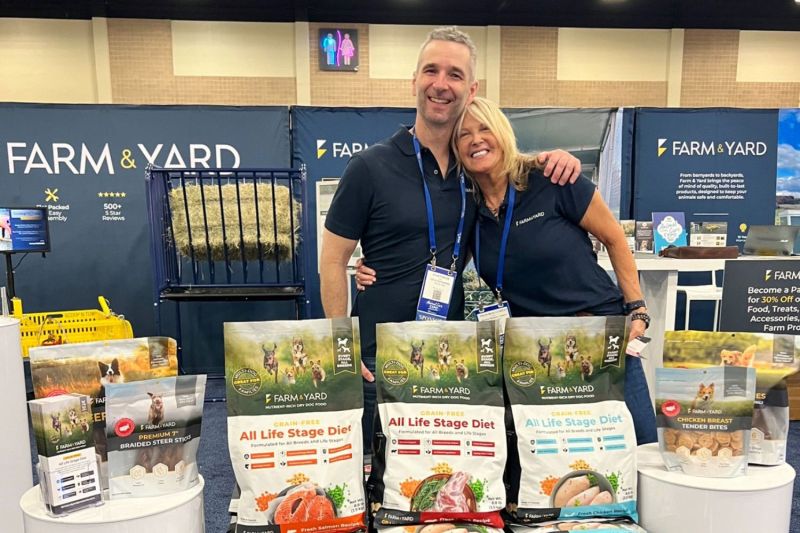 a man and a woman pose surrounded by pet food and brochures