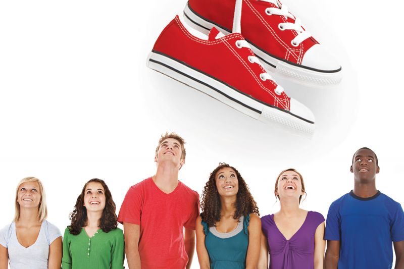 A group of people looking up at a huge pair of shoes