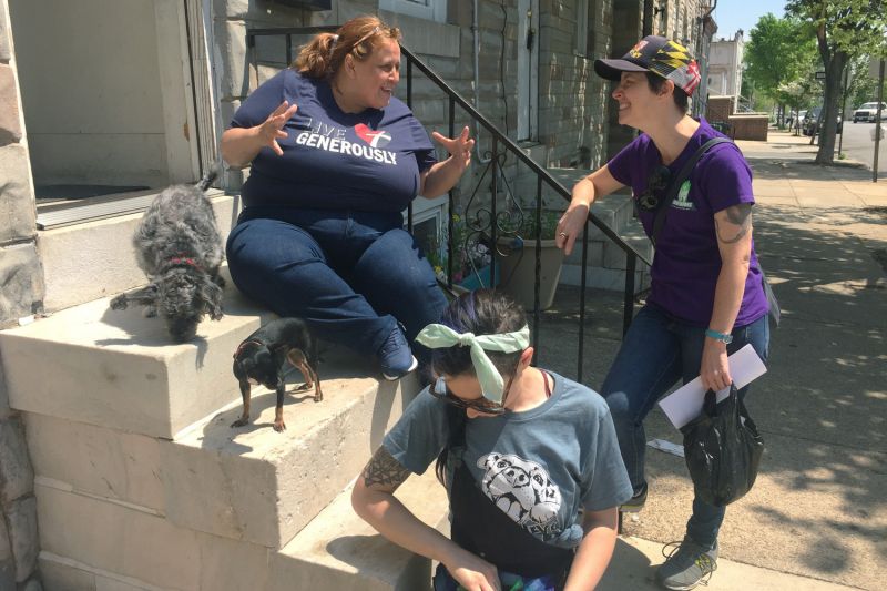 three women talk on a city doorstop