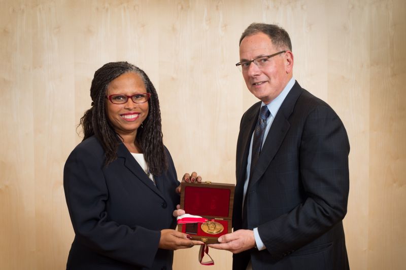 a woman and man hold a medal in a box