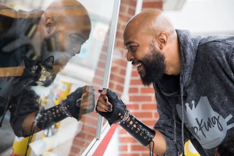 A man leans into the glass to look at a cat in the window