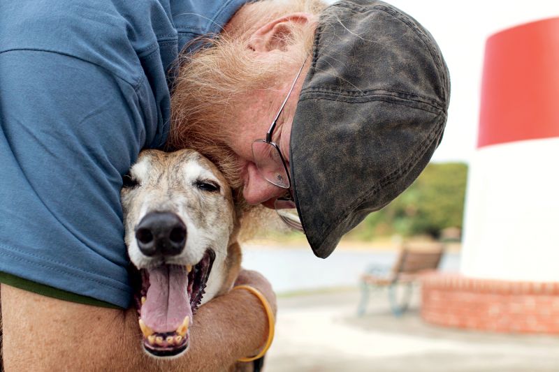 a man kissing an elderly dog