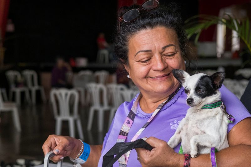 a happy woman looks at her dog nestled in the crook of her arm