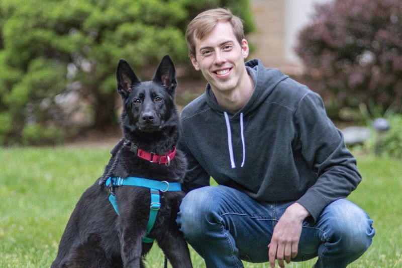 a young man leaning next to his dog