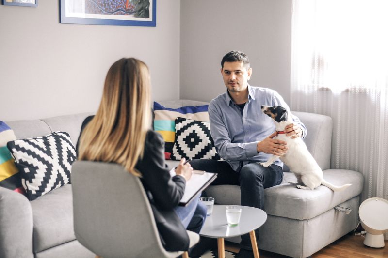 Man having a meeting with veterinary social worker with a dog.