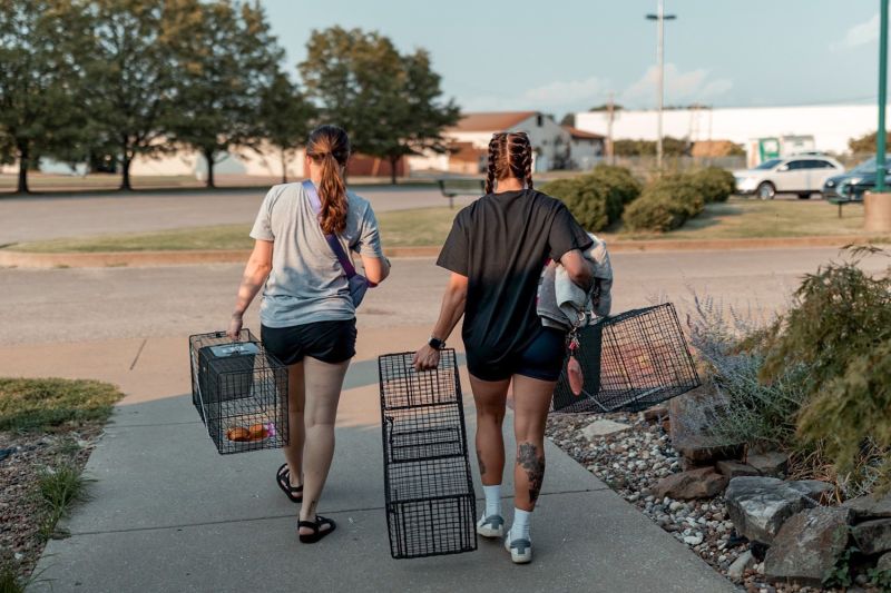 two women walking away carrying humane traps