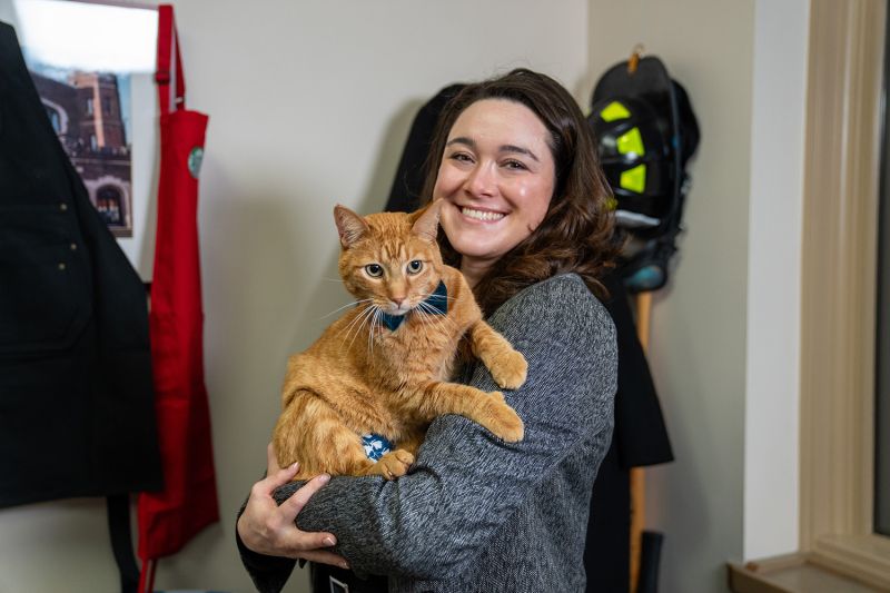 a woman holding an orange cat
