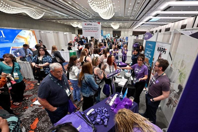 a large group of people speaking with vendors at an exhibit hall