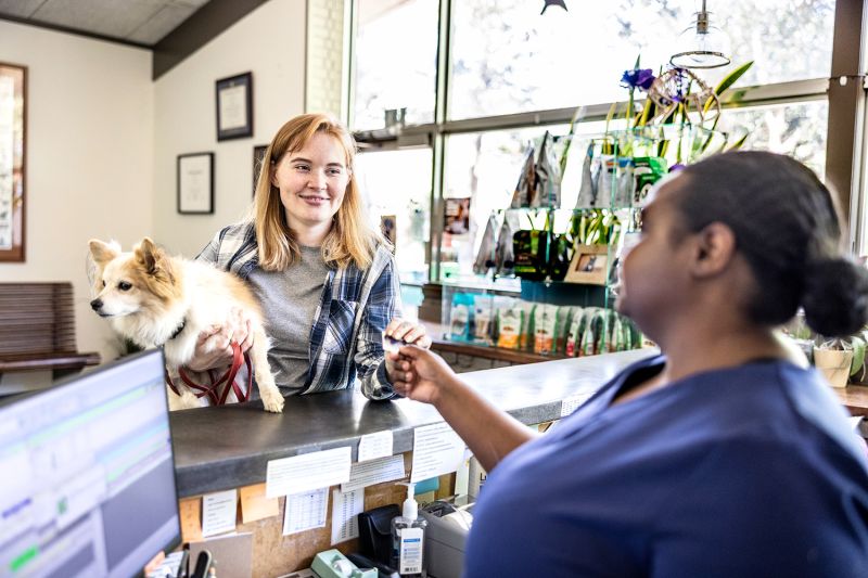 a woman hands her credit card to a vet tech