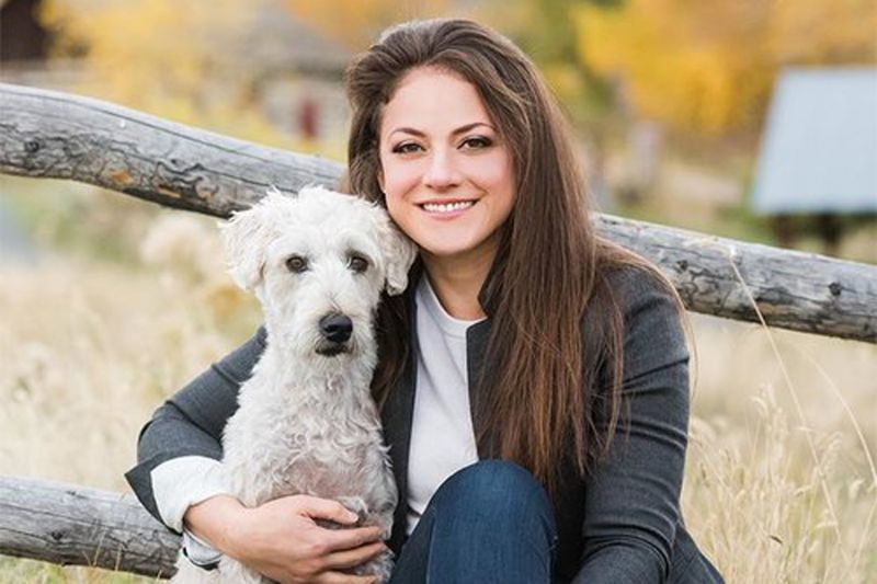 a woman poses with an arm around her dog