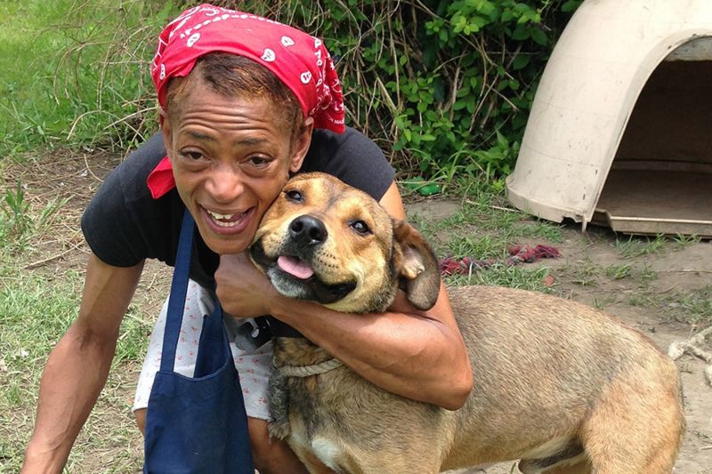 a woman kneeling down to embrace her dog