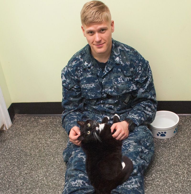 a man in a navy uniform with a cat on his lap