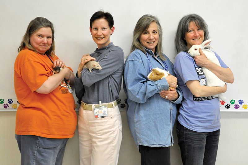 four women pose holding small companion animals