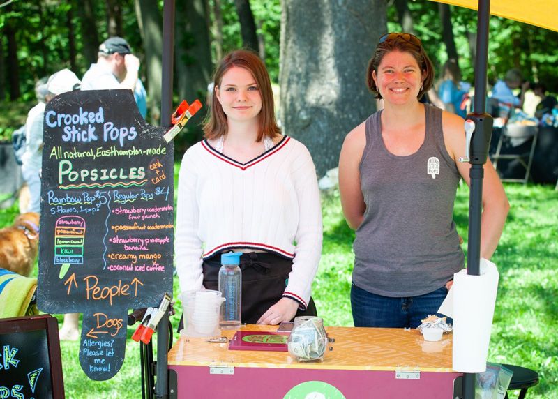 Two women pose next to a menu