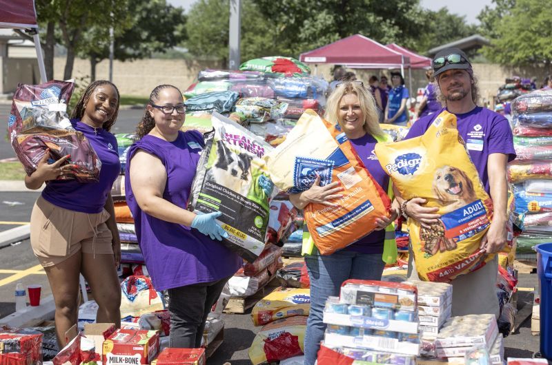 Volunteers holding up bags of pet food