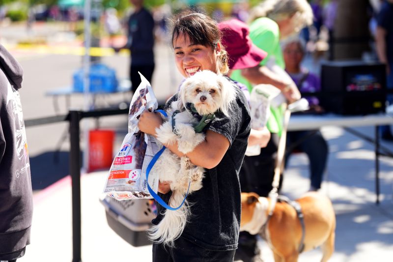 Woman holding a dog and dog food