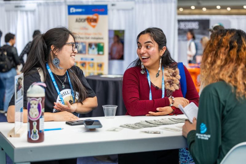 Attendees speaking with an exhibitor smiling
