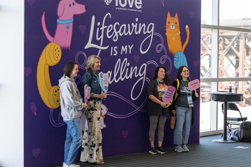 Group of attendees in front of a Petco Love wall