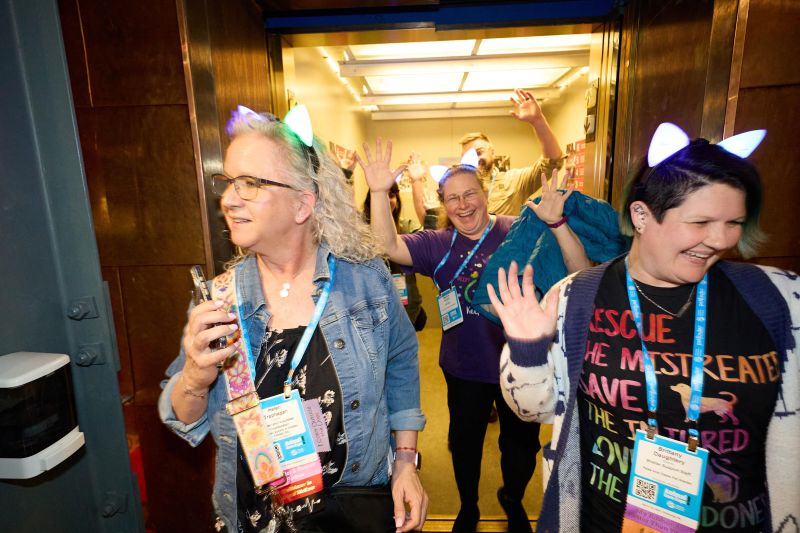 Excited attendees in cat ears coming off an elevator