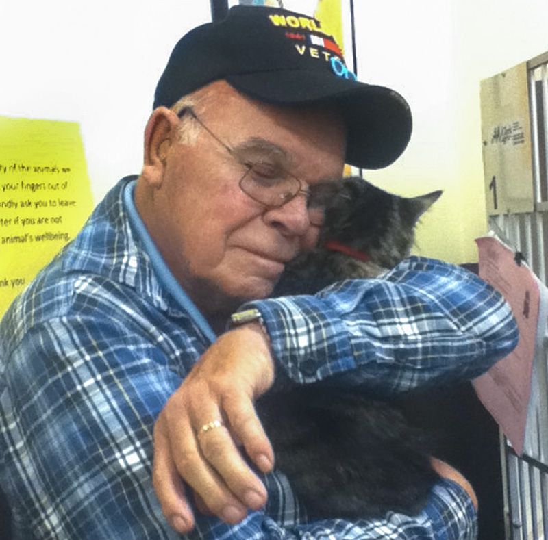 an older man hugs his cat