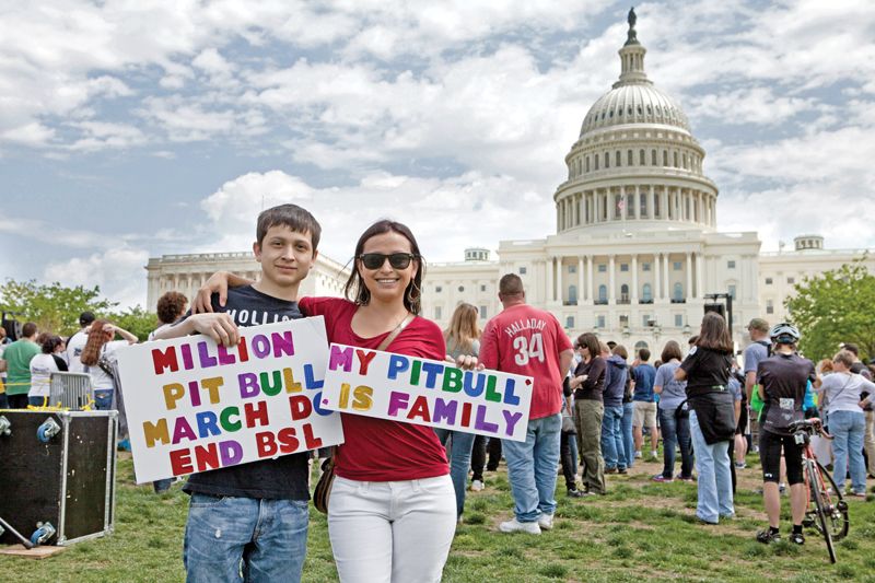 a couple holds signs about repealing BSL in front of the US capitol building