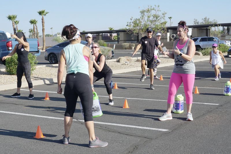 a group of people working out in a parking lot with jugs of cat litter